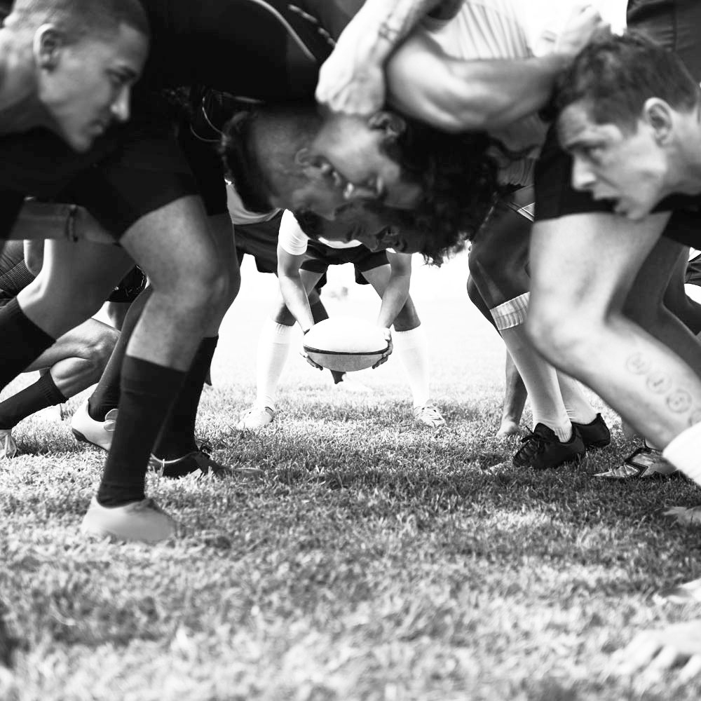 Een zwart-wit close-up foto van een aantal rugby-spelers in een scrum